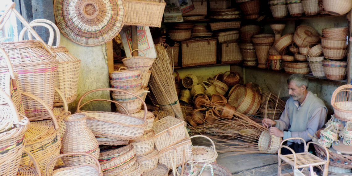 A wicker weaver weaving a basket at his shop in Srinagar