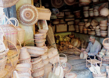 A wicker weaver weaving a basket at his shop in Srinagar