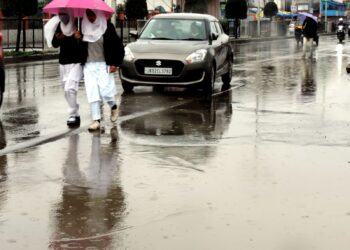 Students walking down the Lal Chowk in Srinagar amid rain fall in Srinagar