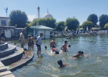 Amid sweltering hot weather conditions children taking bath in the waters of iconic Dal Lake at Hazratbal in Srinagar