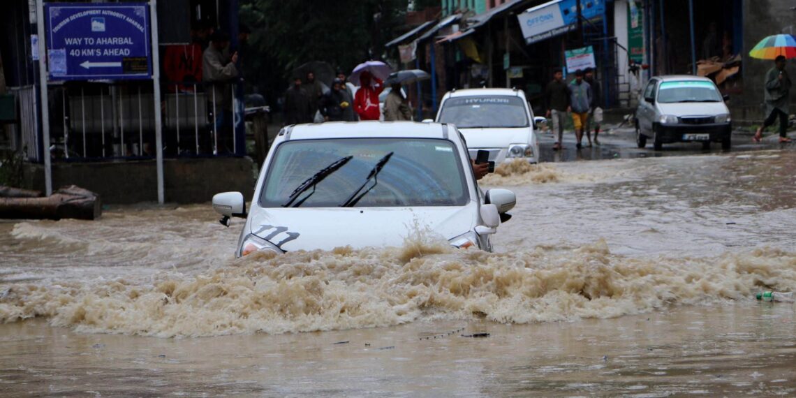 Commuters wade through water-logged road after heavy rain, on Wednesday