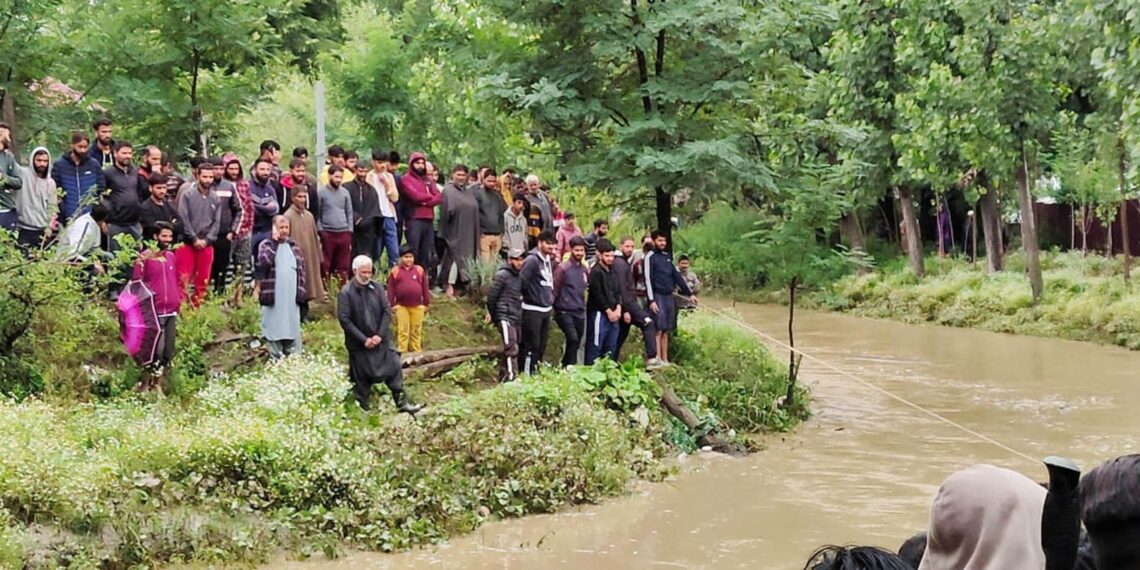 Commuters wade through water-logged road after heavy rain, on Wednesday