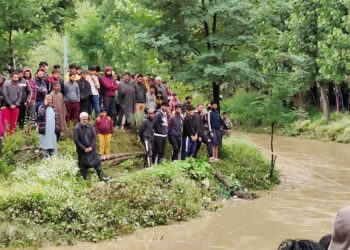 Commuters wade through water-logged road after heavy rain, on Wednesday
