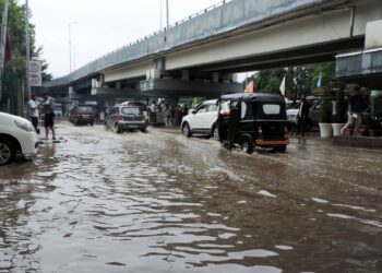 Vehicles passing through a water logged TRC road in Srinagar