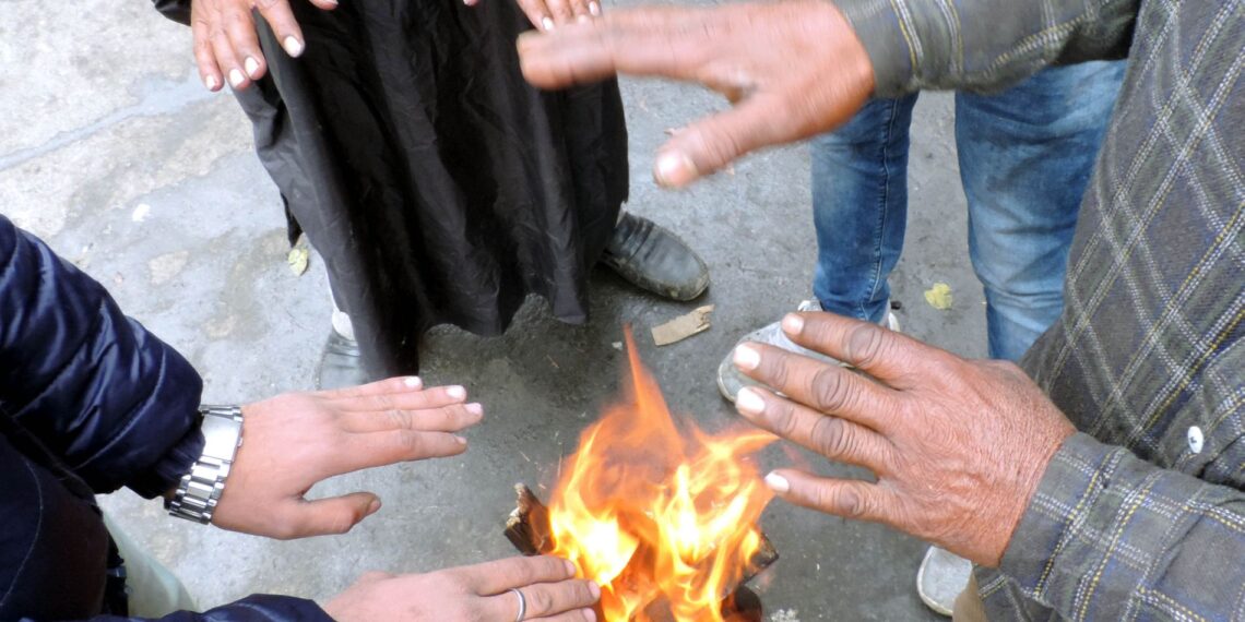 People warm themselves while standing around bonfire in Srinagar following rains and snow