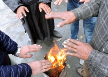 People warm themselves while standing around bonfire in Srinagar following rains and snow